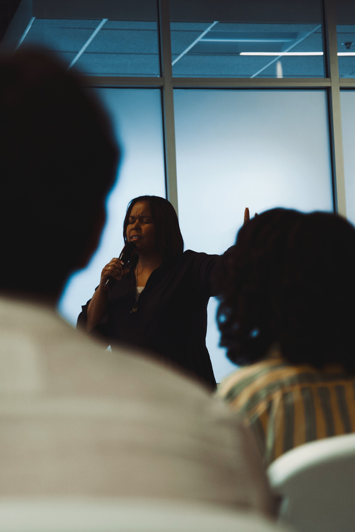 Annette ministering with a microphone among a gathered congregation